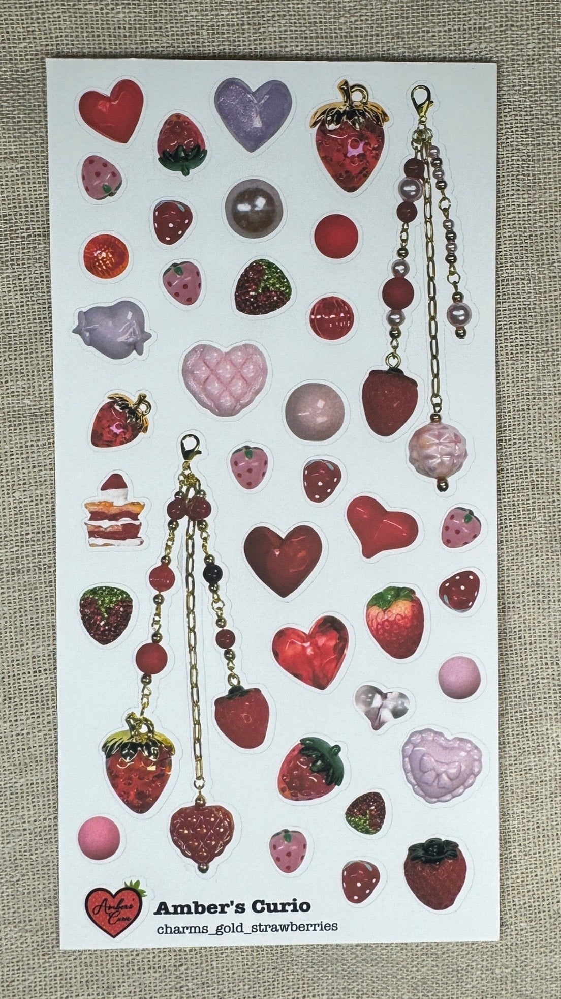 Sticker sheets of photographed strawberry themed red and pink beads and charms printed on premium matte paper photographed on top of linen