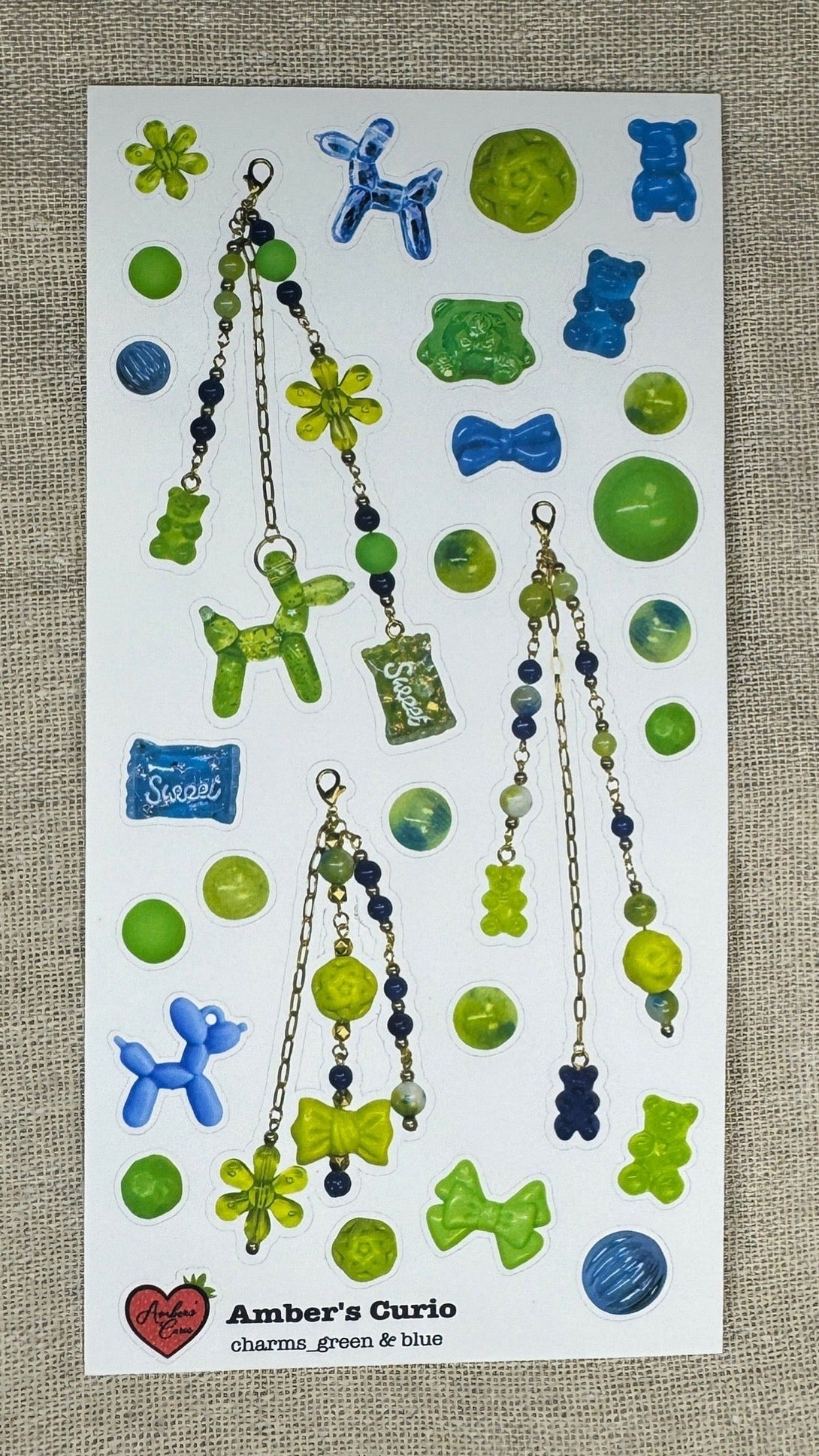 Sticker sheets of photographed bright green and dark blue beads and charms printed on premium matte paper photographed on top of linen