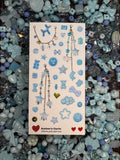 Sticker sheets of photographed light blue beads and charms printed on premium matte paper photographed on top of beads
