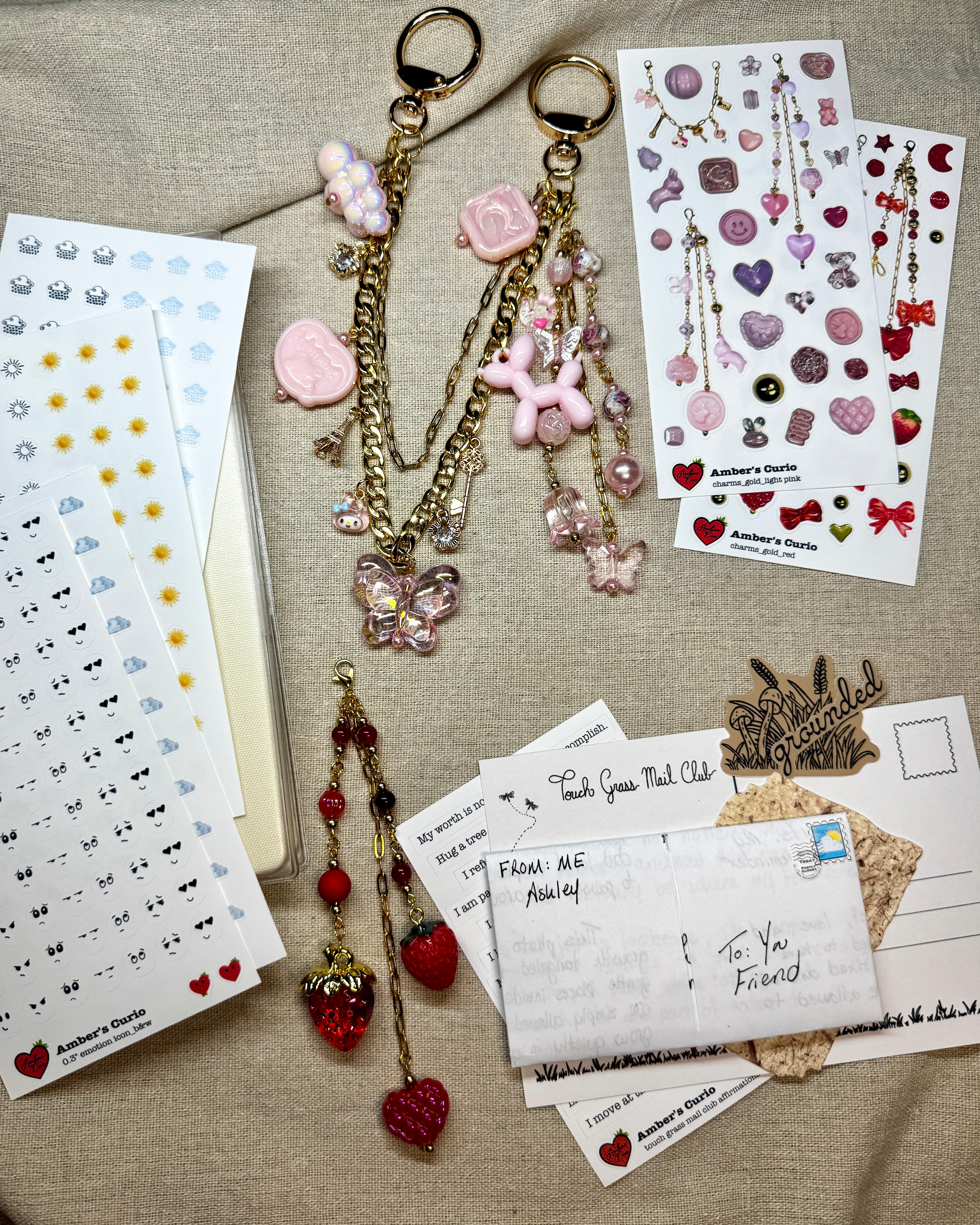 Decorative keychains with embellishments on a textured surface with stationery items.
