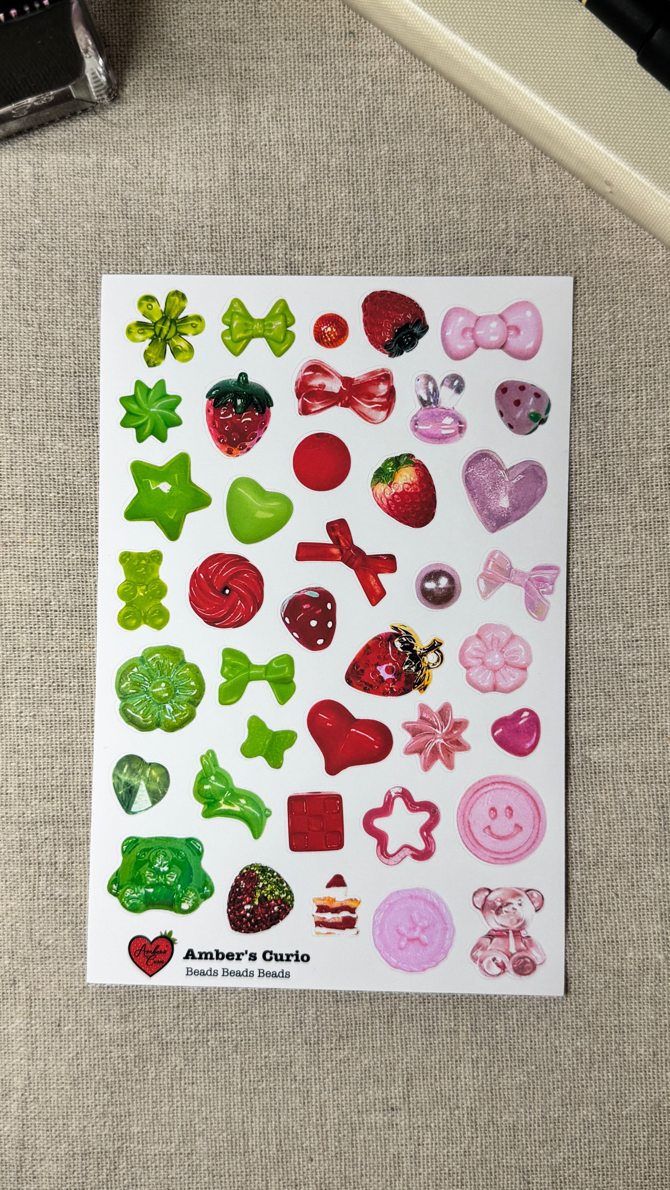Sheet of colorful beads stickers on a textured surface with a pen and notebook in the background.
