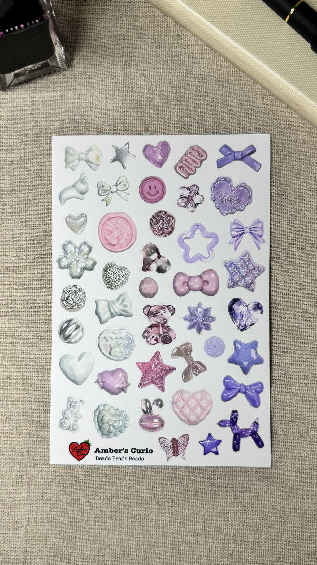 Sheet of decorative beads stickers with various shapes and designs on a textured surface.