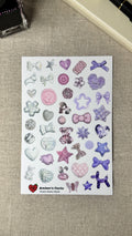 Sheet of decorative beads stickers with various shapes and designs on a textured surface.