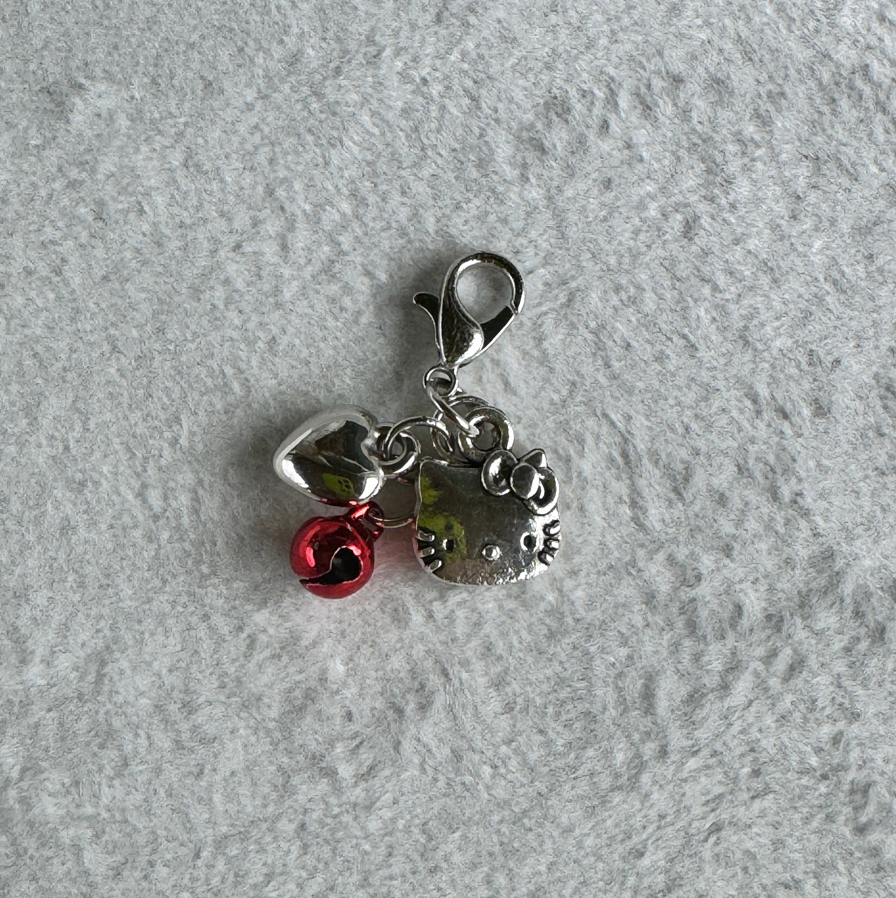 Silver charm with a heart and rose on a gray textured background
