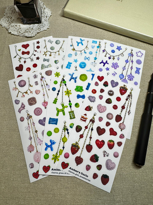 Sticker sheets of photographed beads and charms printed on premium matte paper styled on linen next to a black fountain pen and ink. 