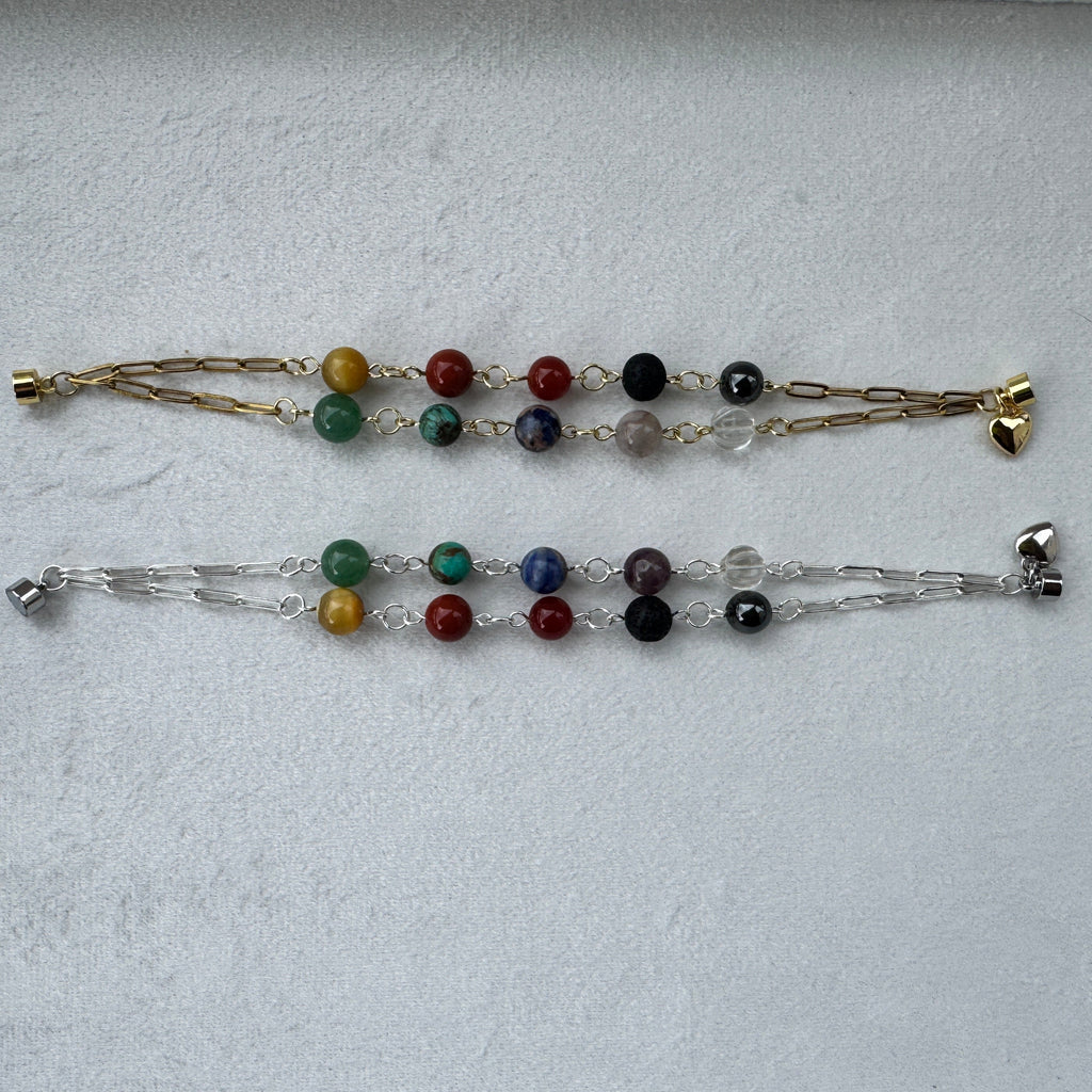 Two gemstone chakra bracelets on a light gray background