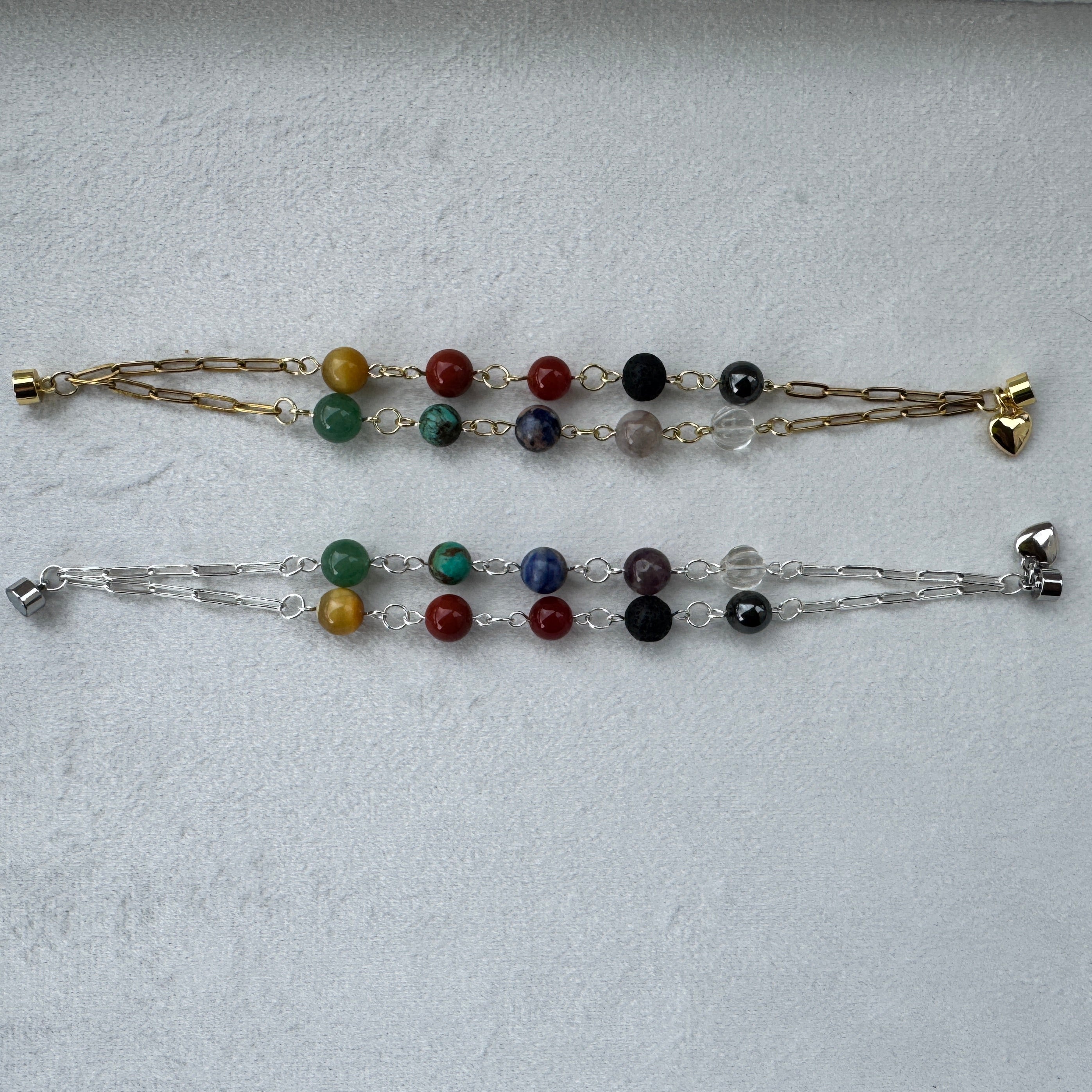 Two gemstone chakra bracelets on a light gray background