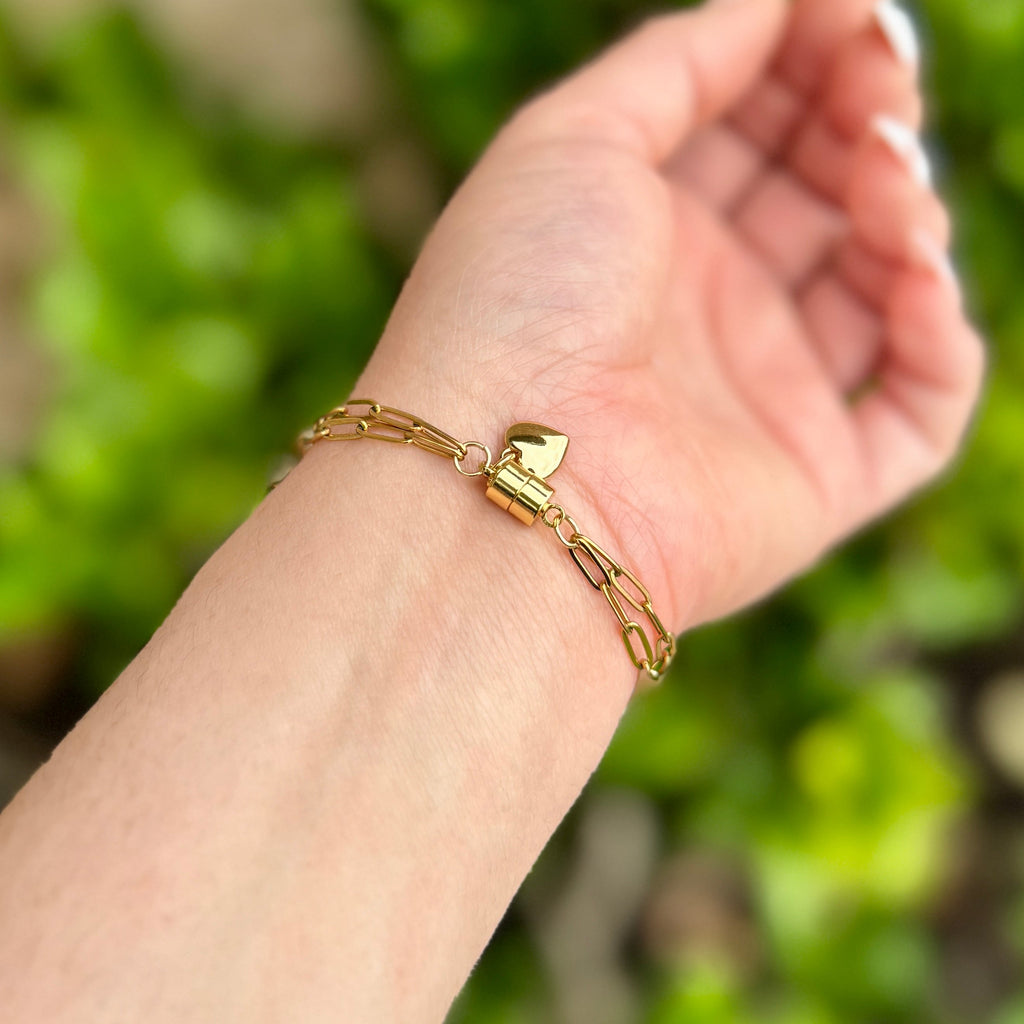 Gold bracelet on a wrist with a blurred green background