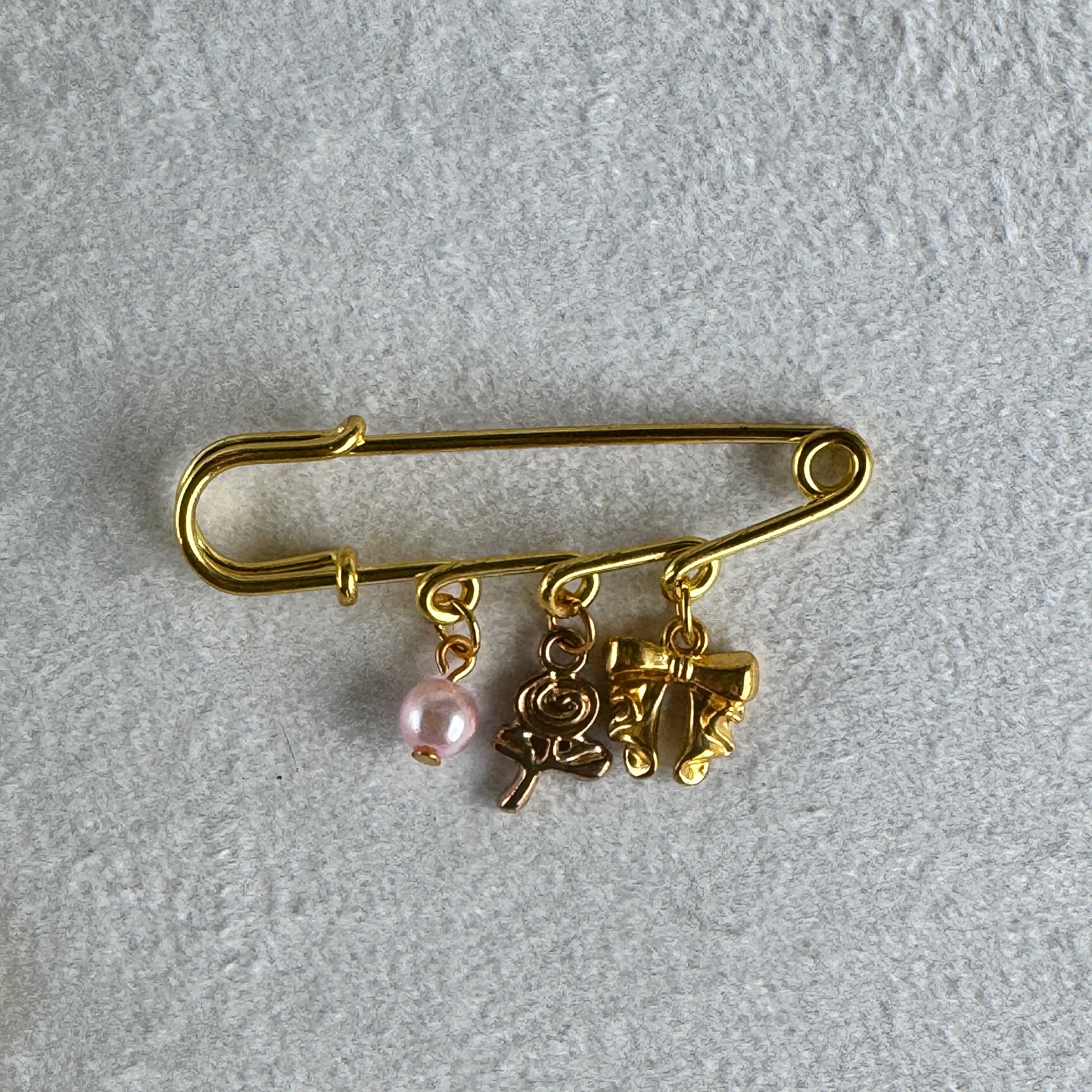 safety pin style brooch gold with a bow and lollipop charm