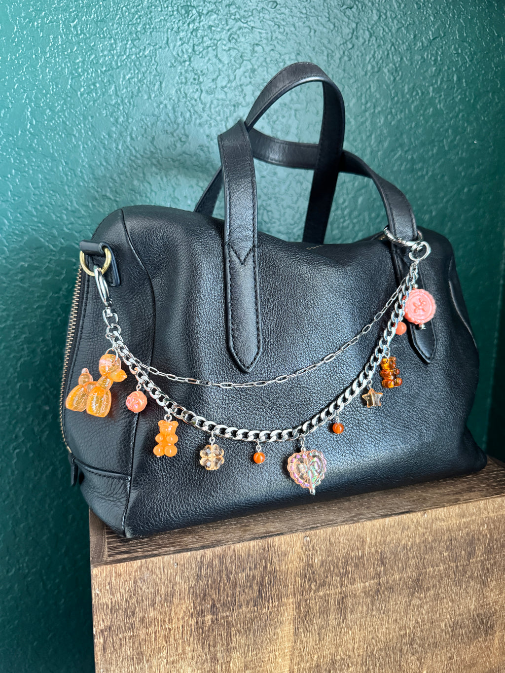 Black backpack with orange tones charms on a green surface