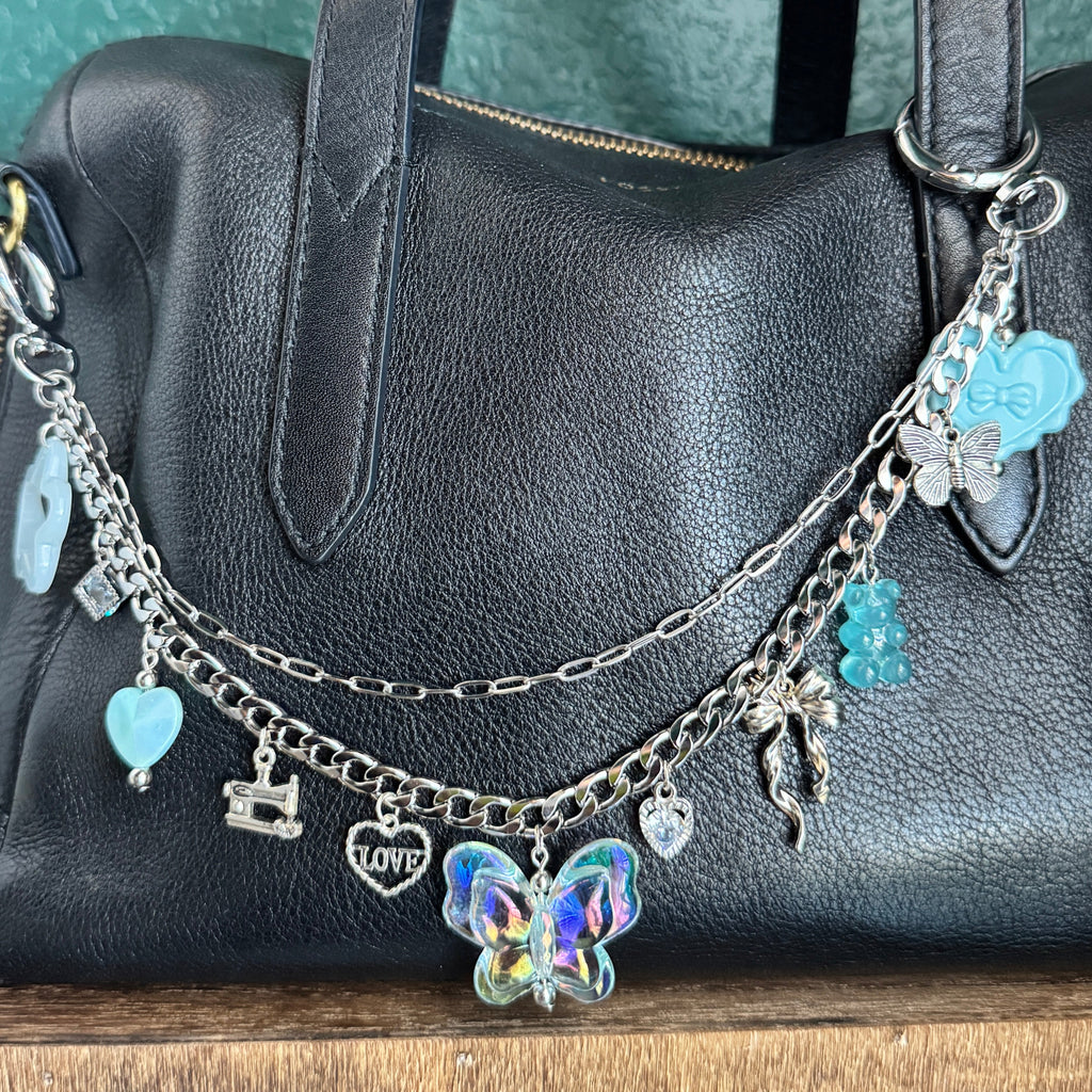 Black handbag with decorative charm on a green surface