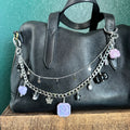 Black leather glove with silver chain and charms on a green surface