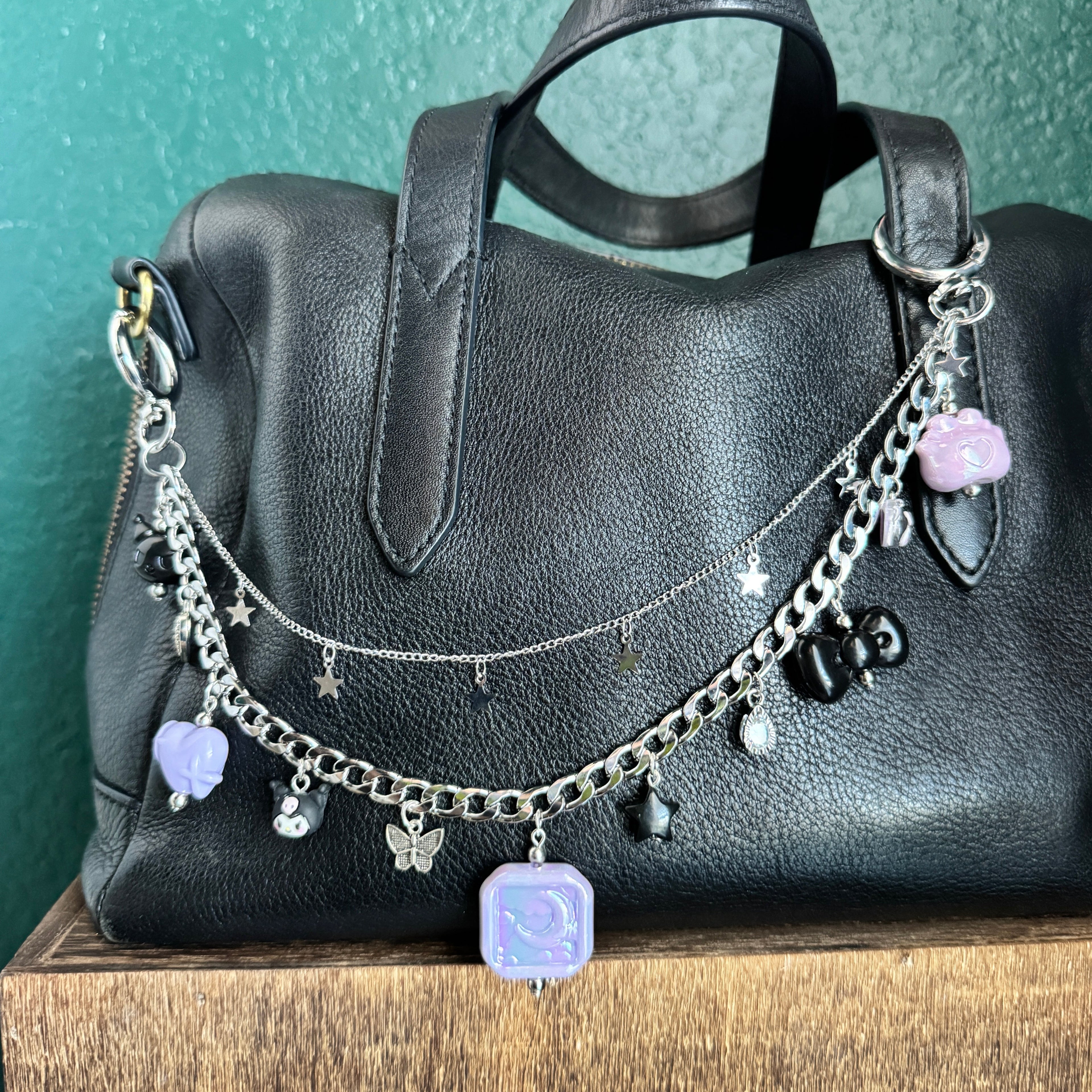 Black leather glove with silver chain and charms on a green surface