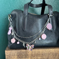 Black leather bag with decorative chain and charms on a green surface