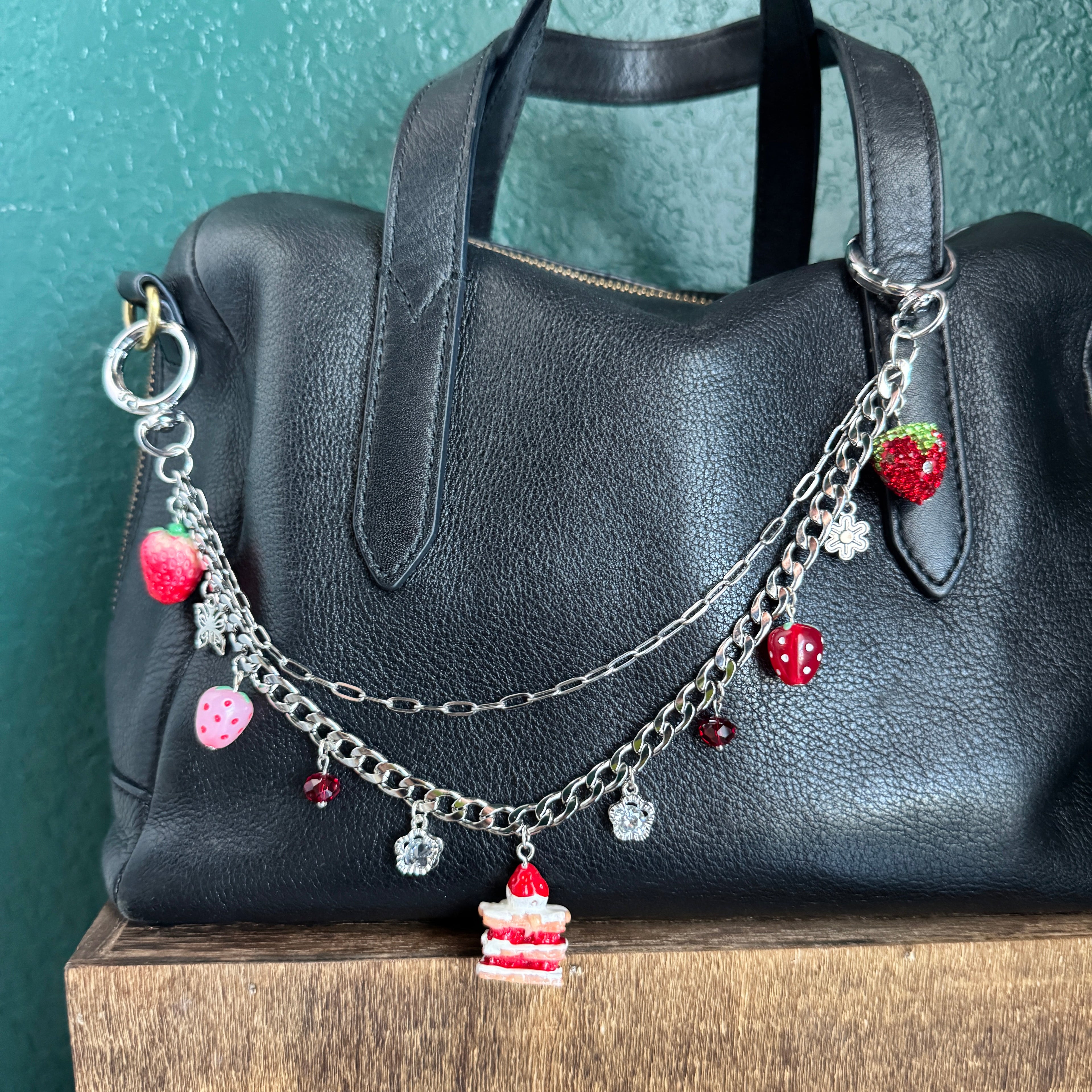 Bracelet with colorful charms on a black leather bag against a wooden surface.