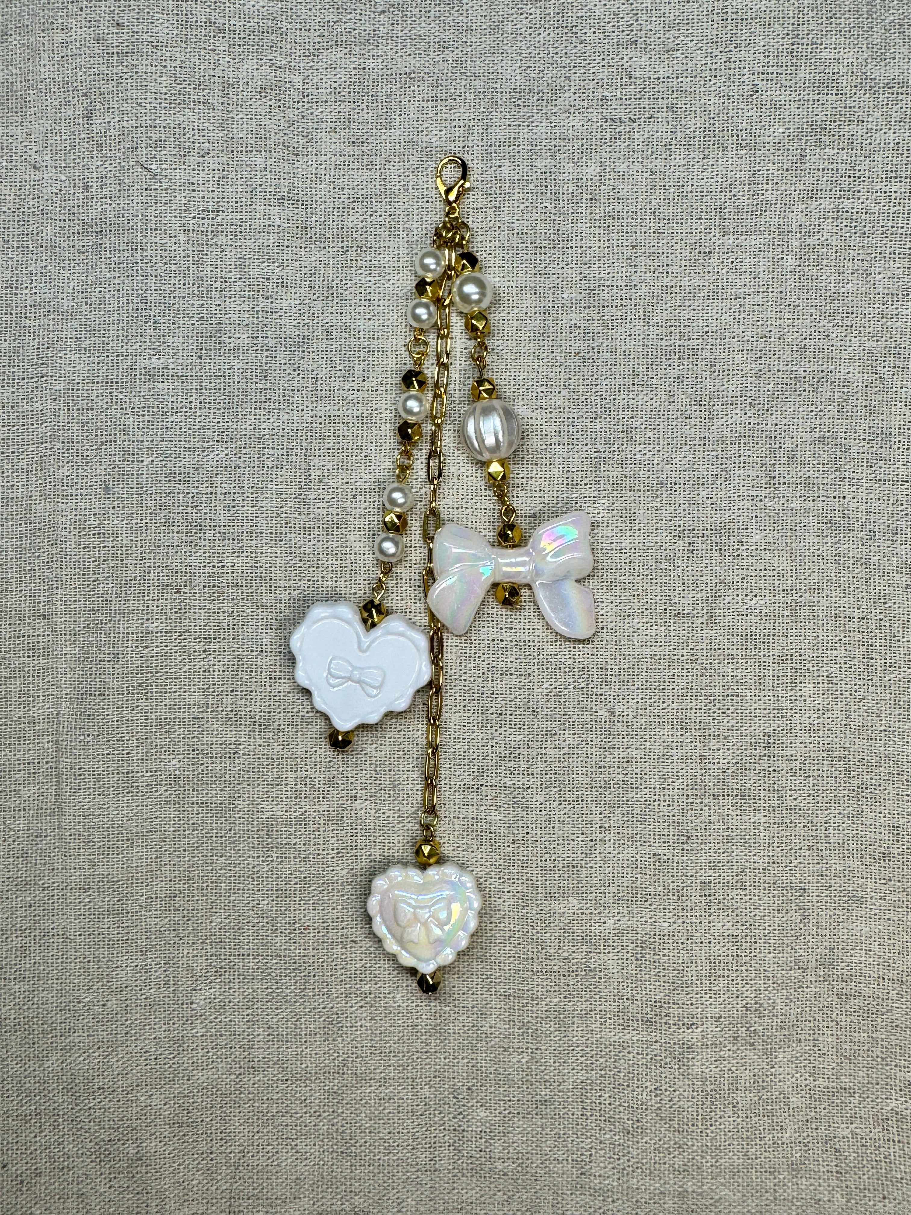 Decorative white journal charm with heart and bow shapes on top of linen background