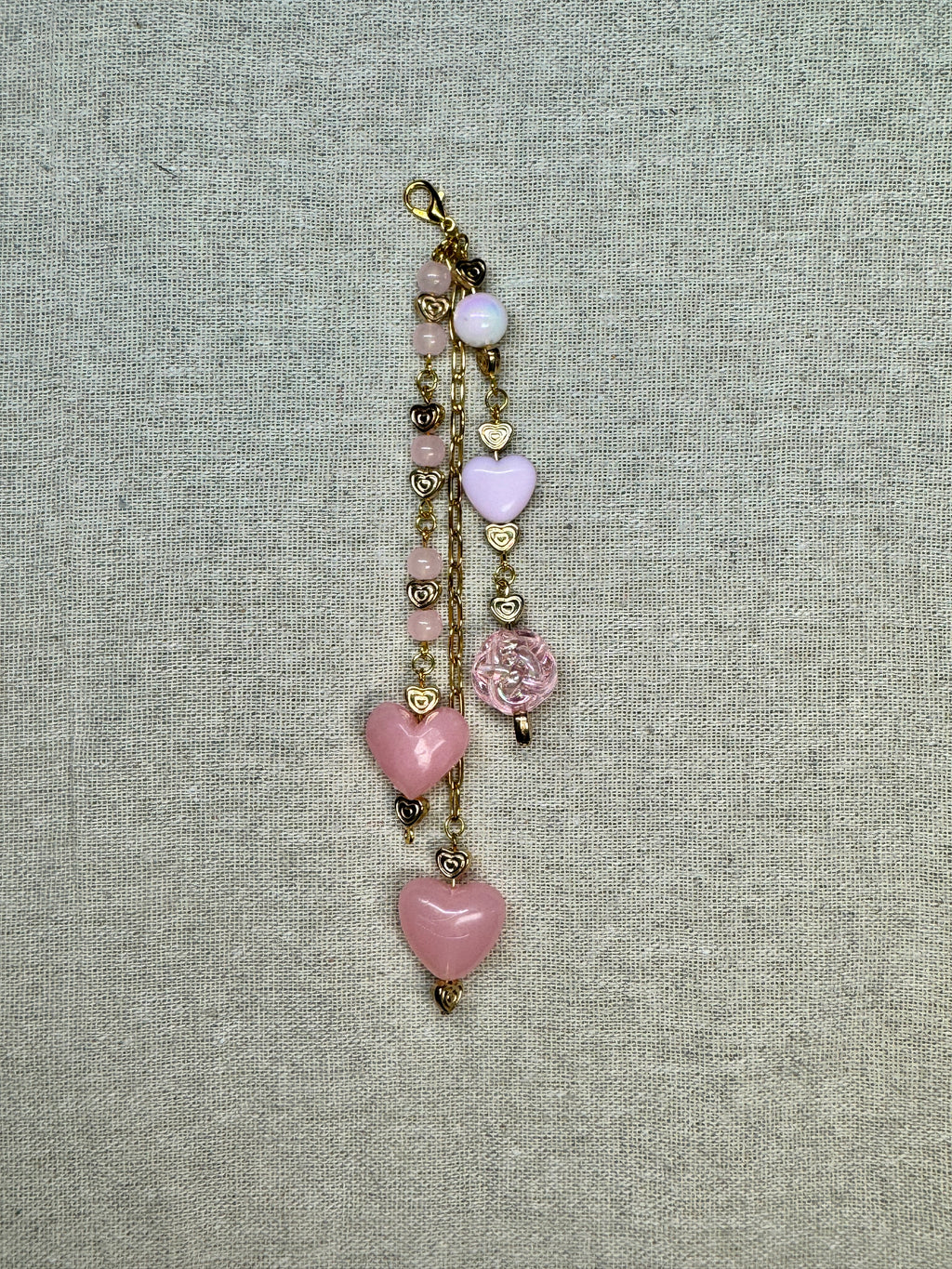 Beaded journal charm with pink heart-shaped beads on linen fabric background