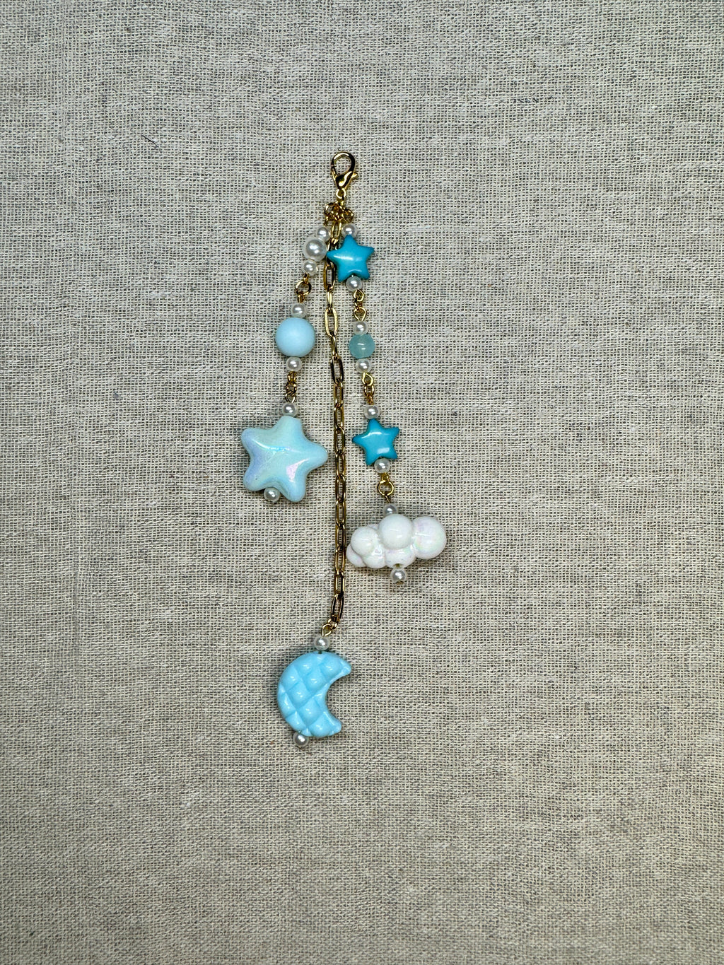 Decorative journal charm with star and moon charms on a textured fabric background