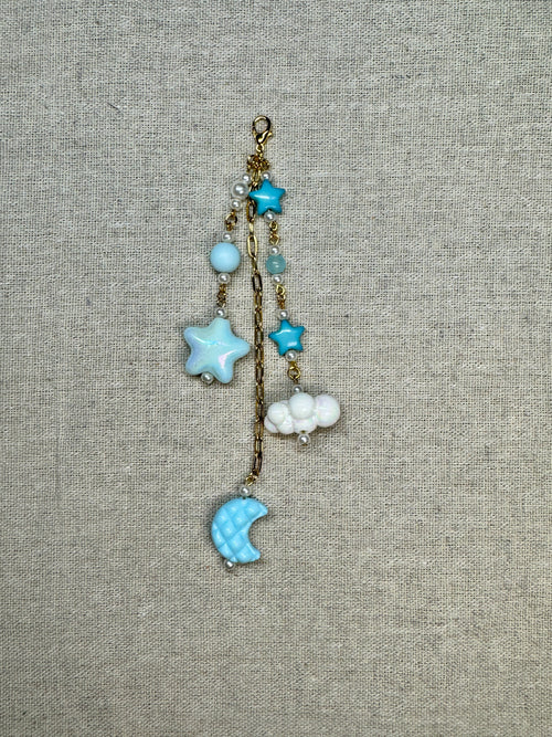 Decorative journal charm with star and moon charms on a textured fabric background