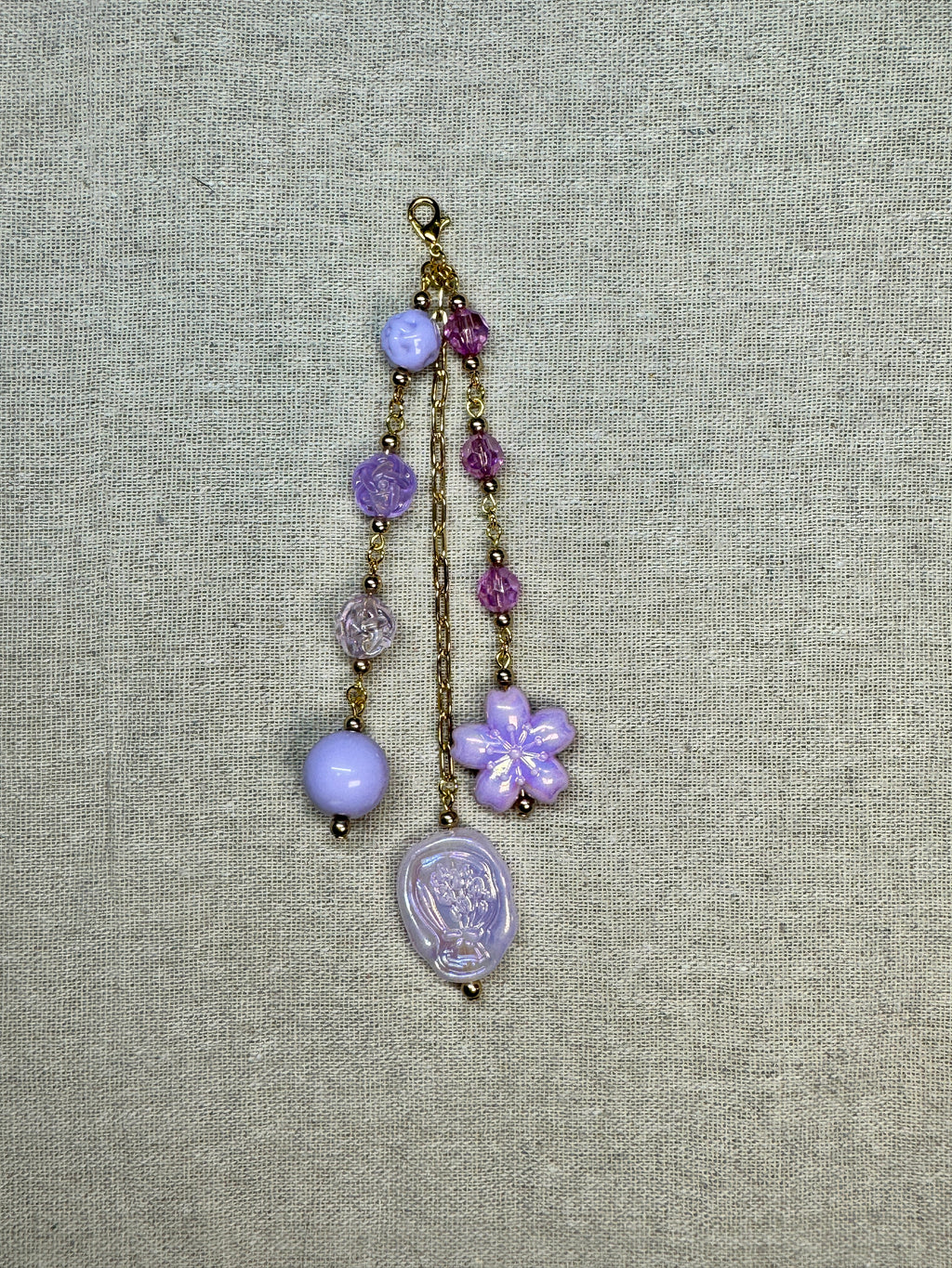 Decorative journal charm with beads and a flower charm on a textured fabric background