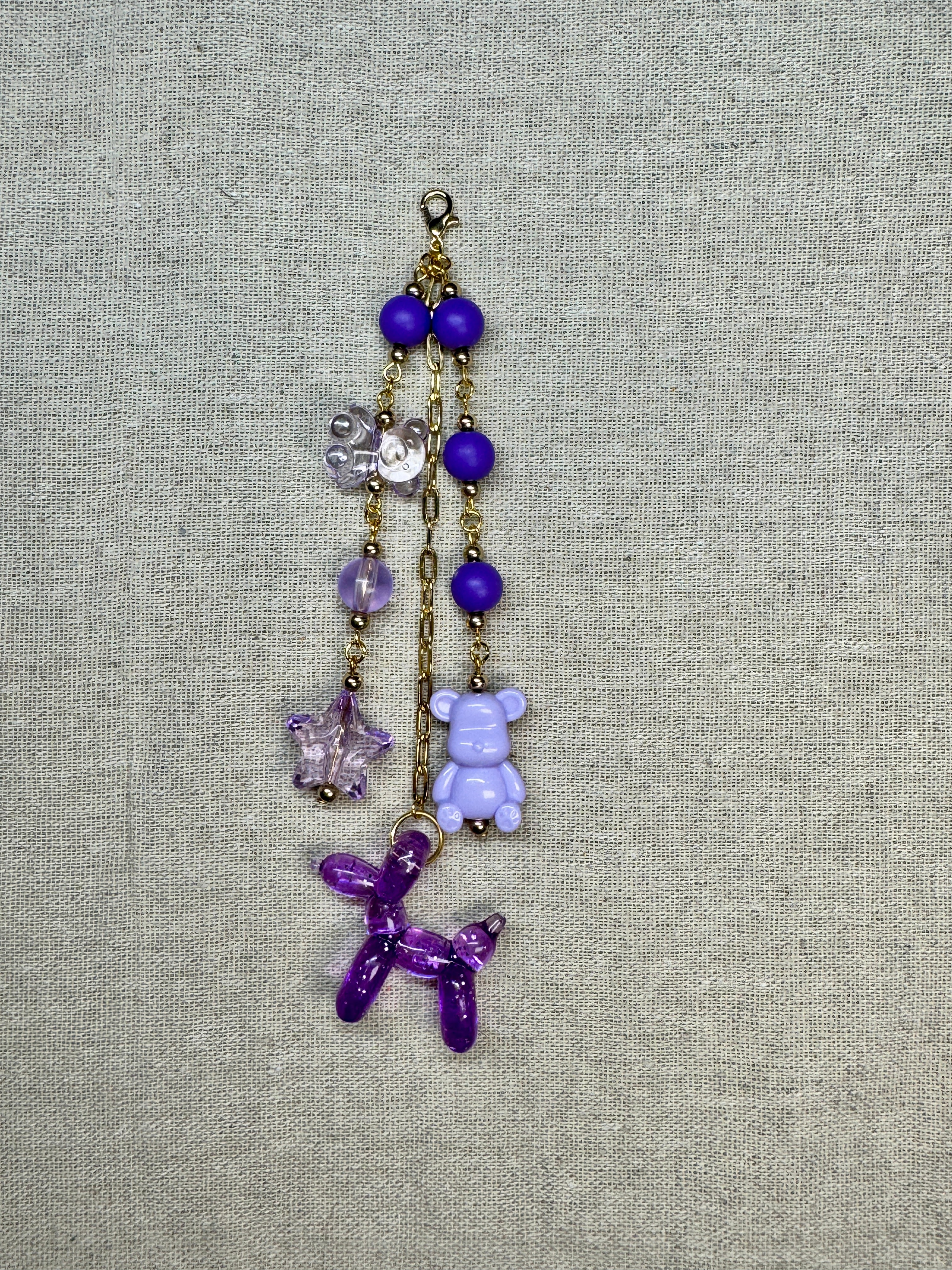 Decorative journal charm with purple and gold elements on a textured gray background