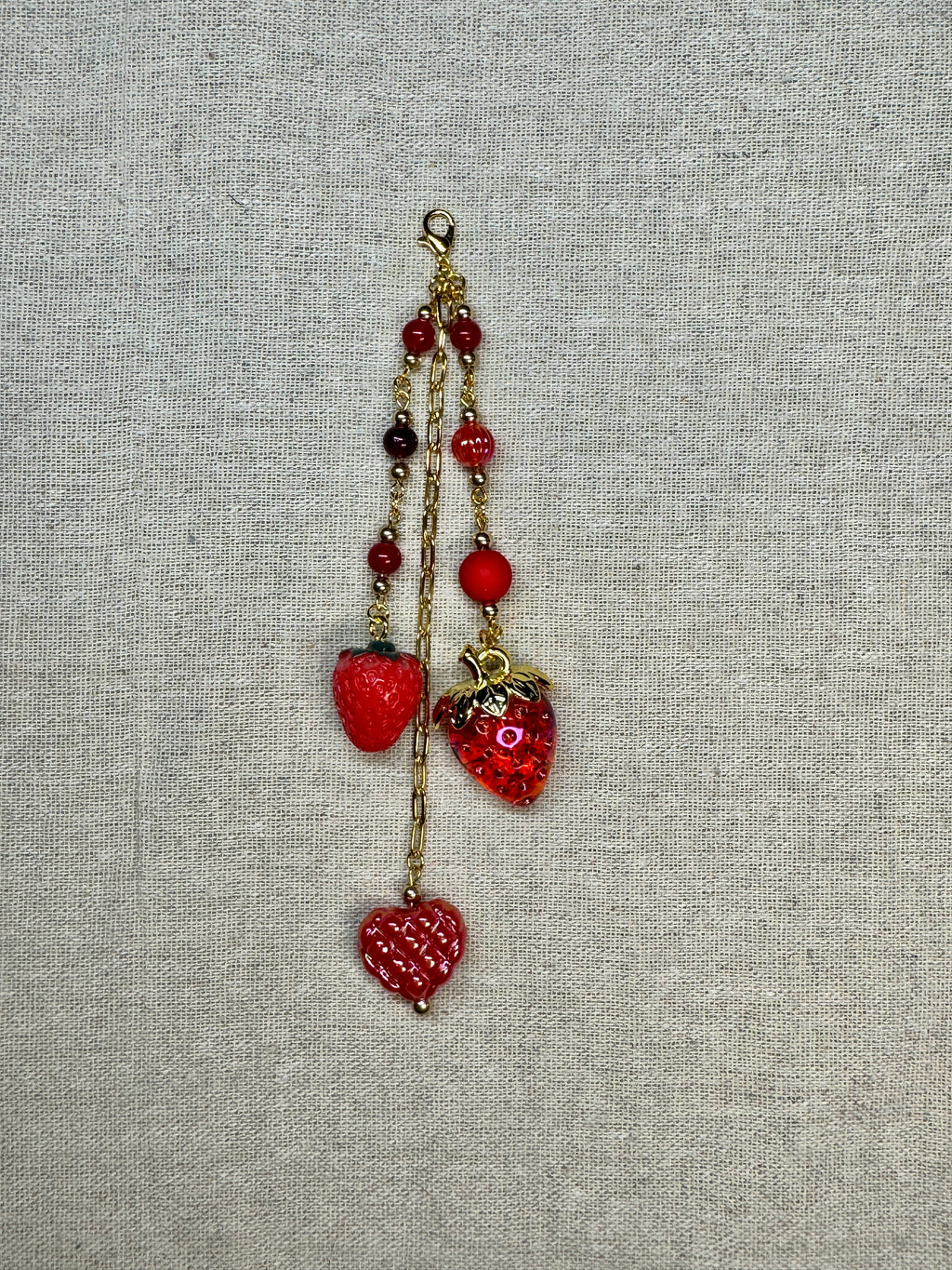 Red Strawberry shaped journal charm with red beads on a textured gray background