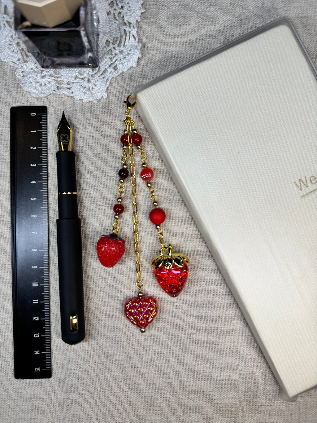 Decorative red journal charm with red heart-shaped on top of linen with a ruler for scale.