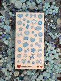 A sticker sheet of photographed light blue beads printed on premium matte paper photographed on top of beads. 