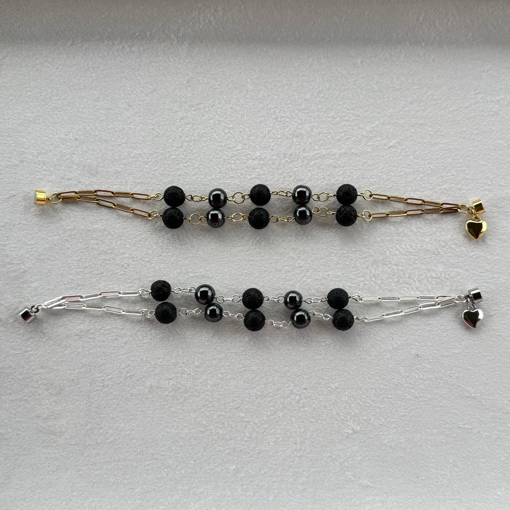Two bracelets one gold and one silver with lava and magnetic hematite stone beads. 