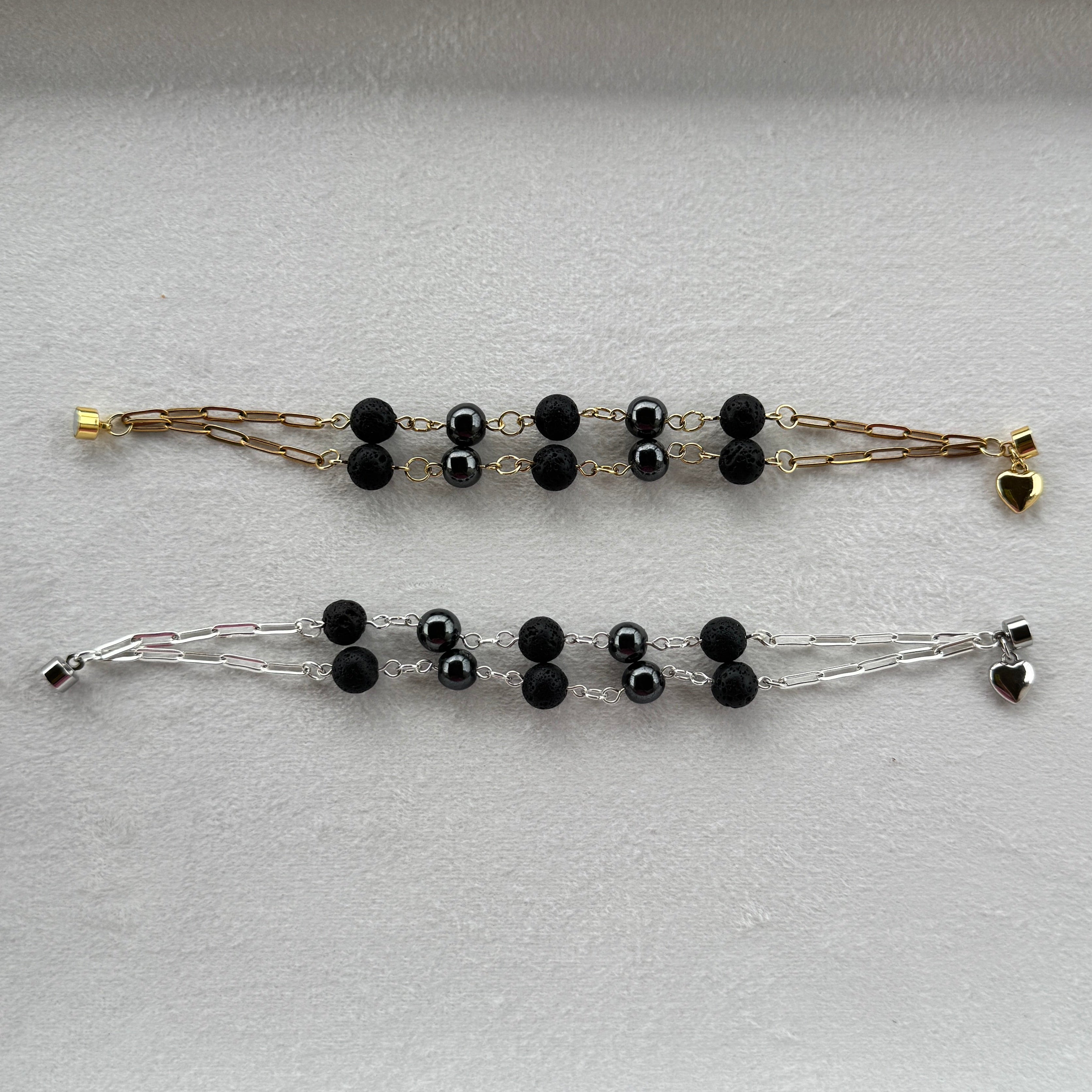 Two bracelets one gold and one silver with lava and magnetic hematite stone beads. 