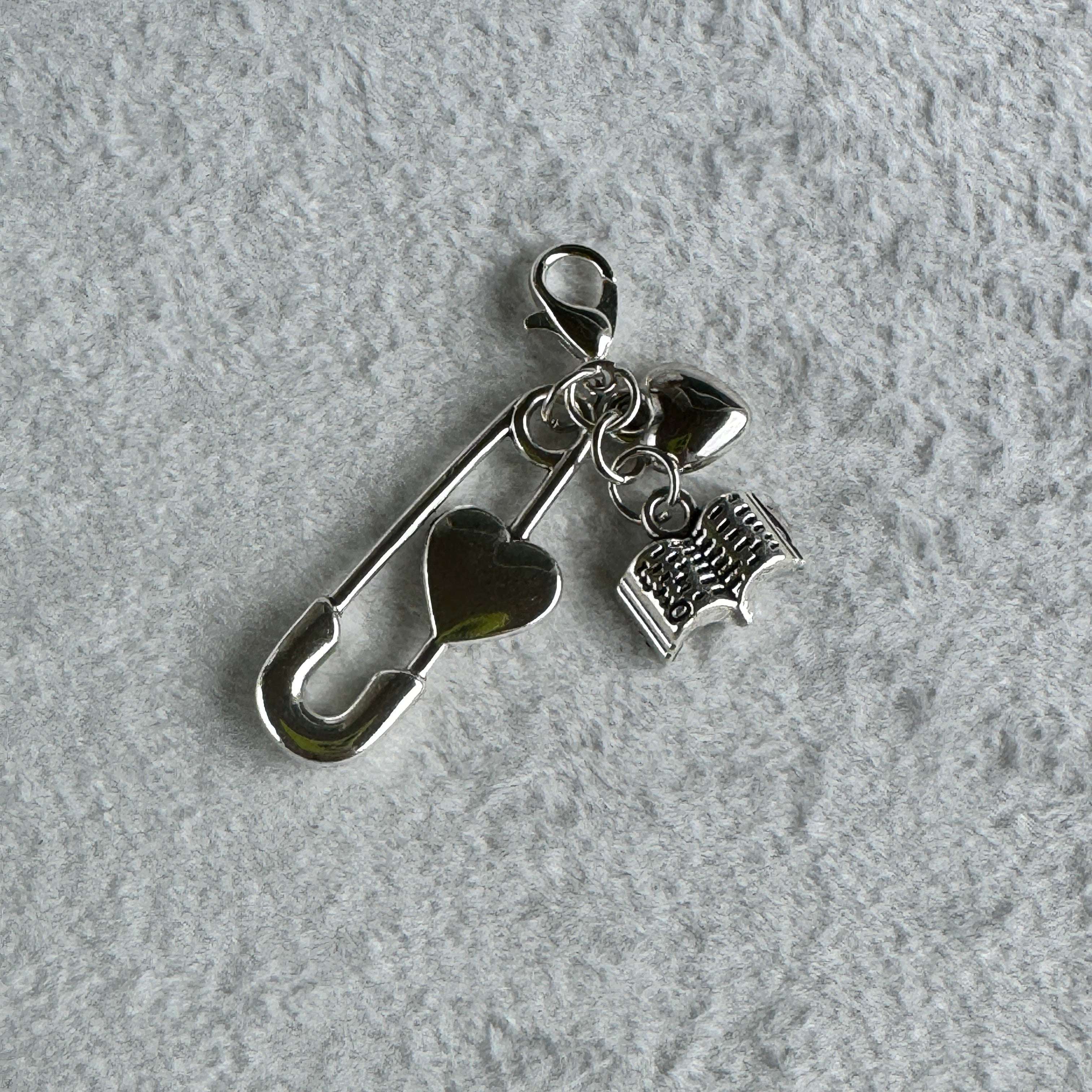 Silver mini charm with a paper clip heart style charm and a book charm 
