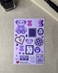 Sticker sheet of a teddy bear within stamp shapes and kawaii themed doodles next to a journal fountain pink and an ink bottle. 